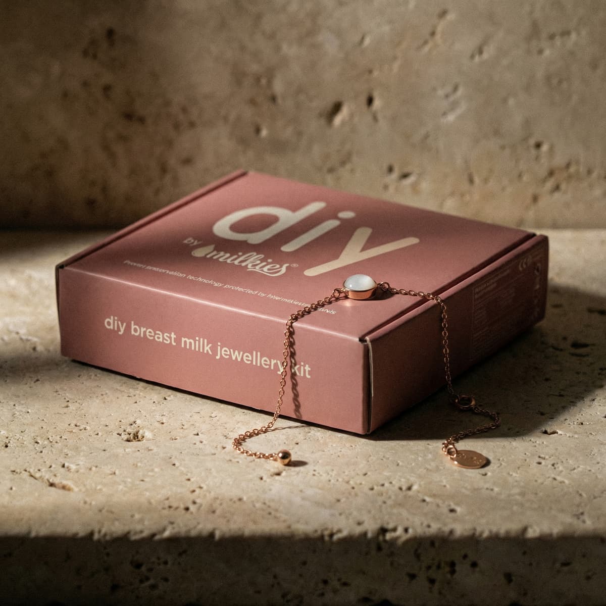 Pink DIY by MILKIES diy breast milk jewellery kit box featuring a rose-gold bracelet and white resin stone, showing an at-home breastmilk bracelet making kit for creating keepsake jewelry.