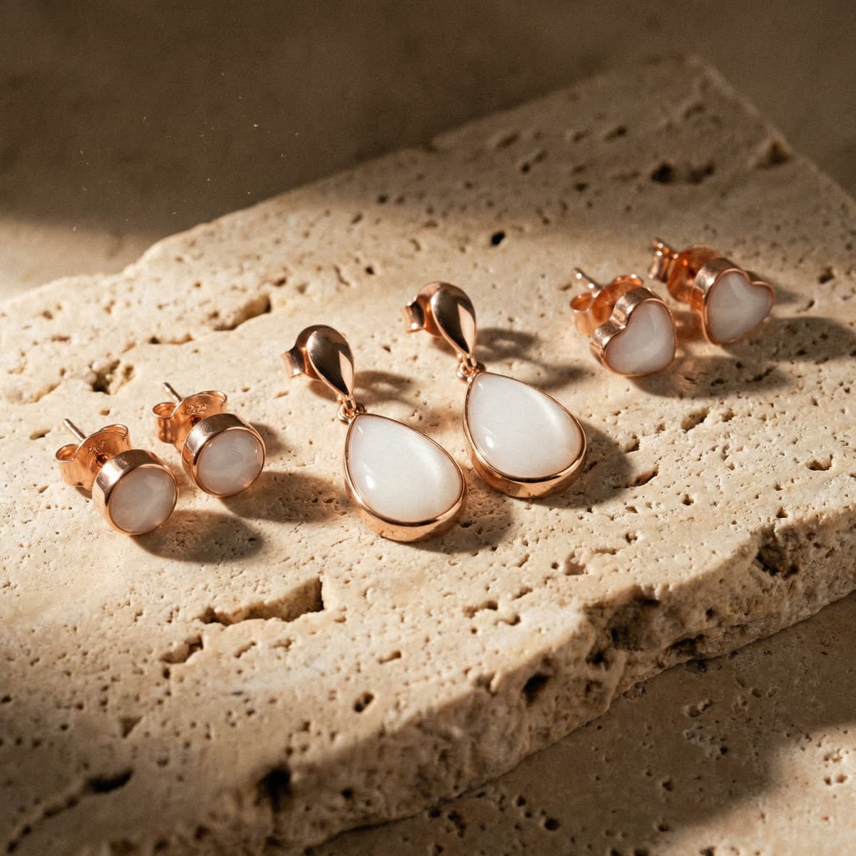 Rose gold teardrop and heart stud keepsake earrings on a stone surface, created with a breastmilk earrings making kit for a creamy white resin finish.