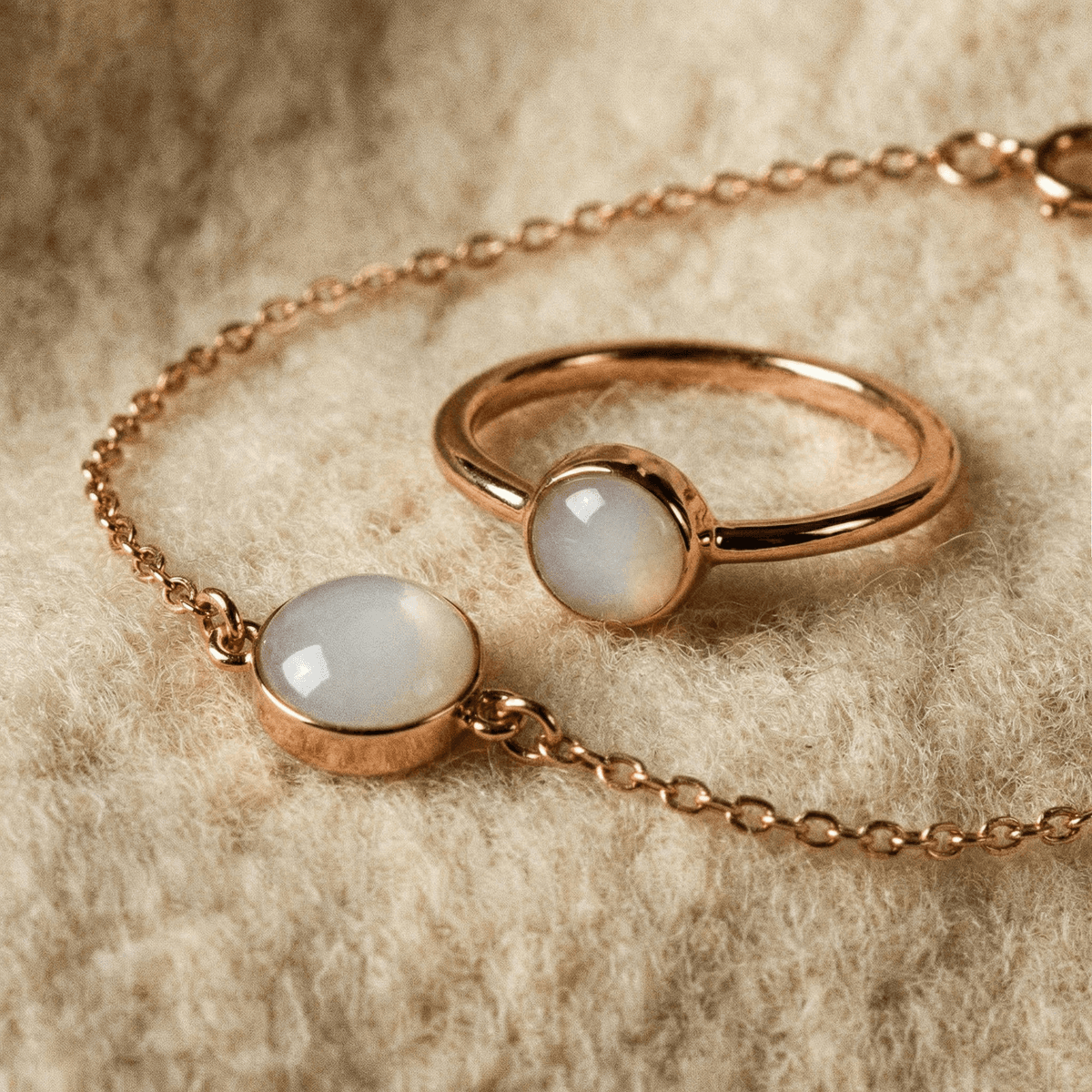 Rose gold ring and matching bracelet featuring milky white resin stones, showcasing handmade breastmilk rings on a soft beige fabric background