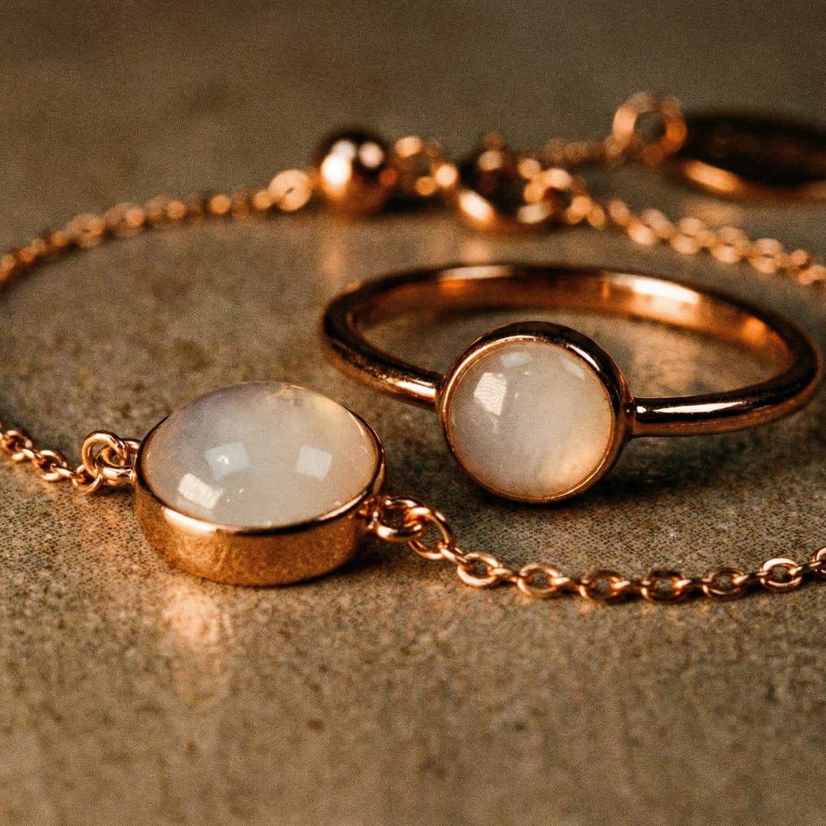 Rose-gold jewelry close-up featuring a milky white resin stone diy breastmilk bracelet with a matching ring on a textured surface
