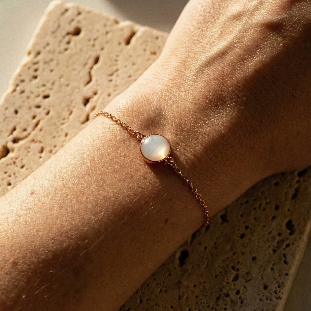 Close-up of a wrist wearing a delicate gold chain bracelet with a round milky-white resin stone, ideal for diy breastmilk bracelets and handmade keepsake jewelry.
