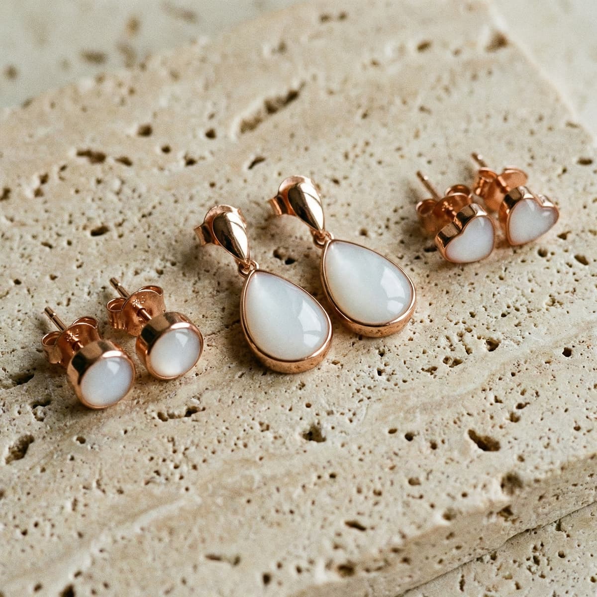 Rose gold teardrop and heart stud jewelry sets with milky white resin stones, perfect for diy breastmilk earrings keepsake making, displayed on a textured stone background.
