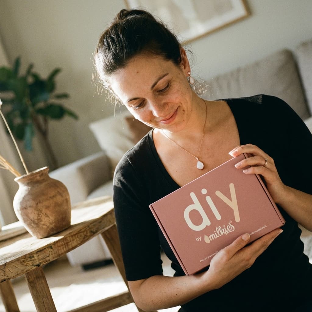 Mother smiling at home while holding a DIY by MILKIES box, showing why a diy breastmilk jewellery kit is a convenient, private, hands-on way to create a personal keepsake.