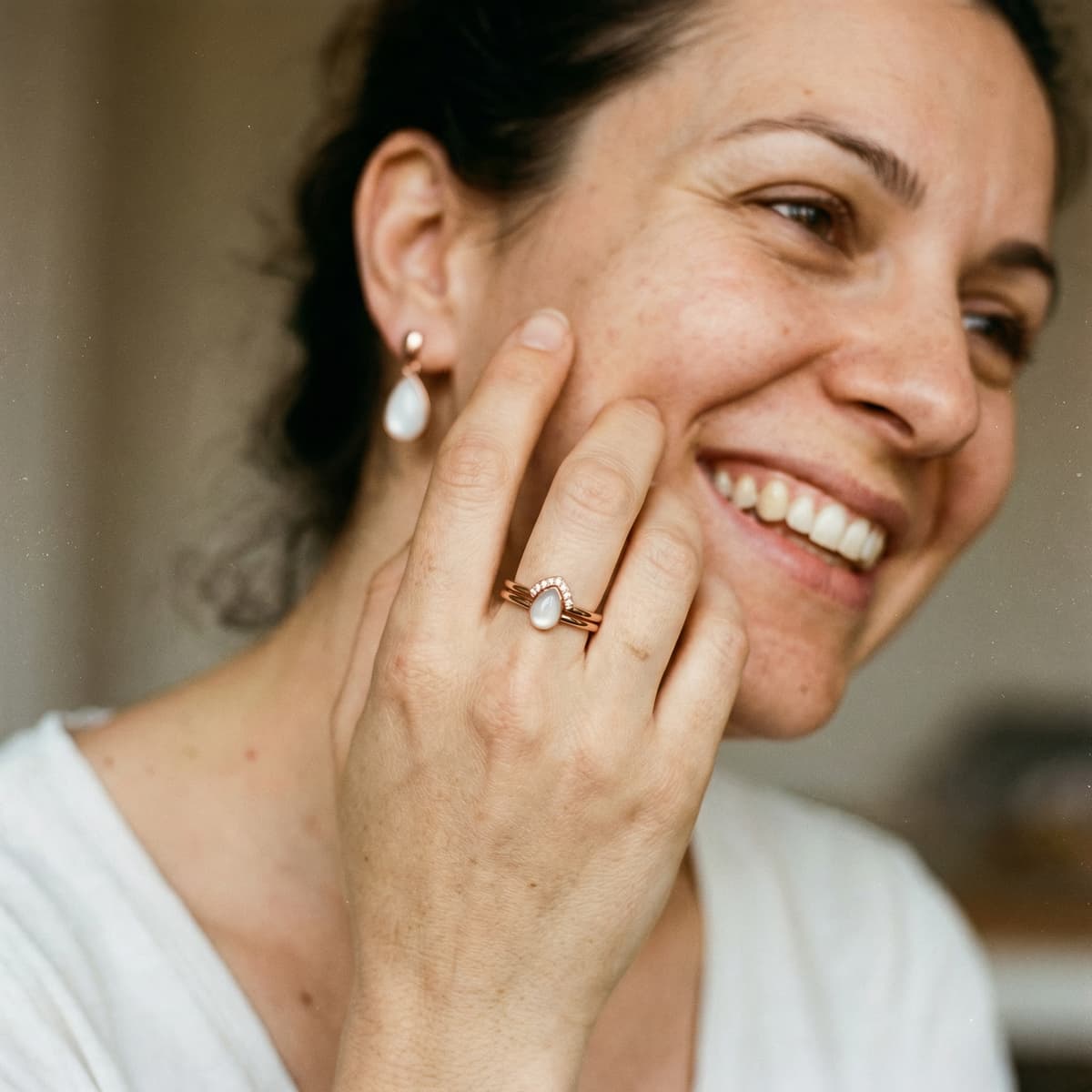Smiling woman wearing a rose-gold ring with a milky-white breastmilk stone, showing why a diy breastmilk ring kit by DIY by MILKIES is a meaningful, private way to create your keepsake at home.