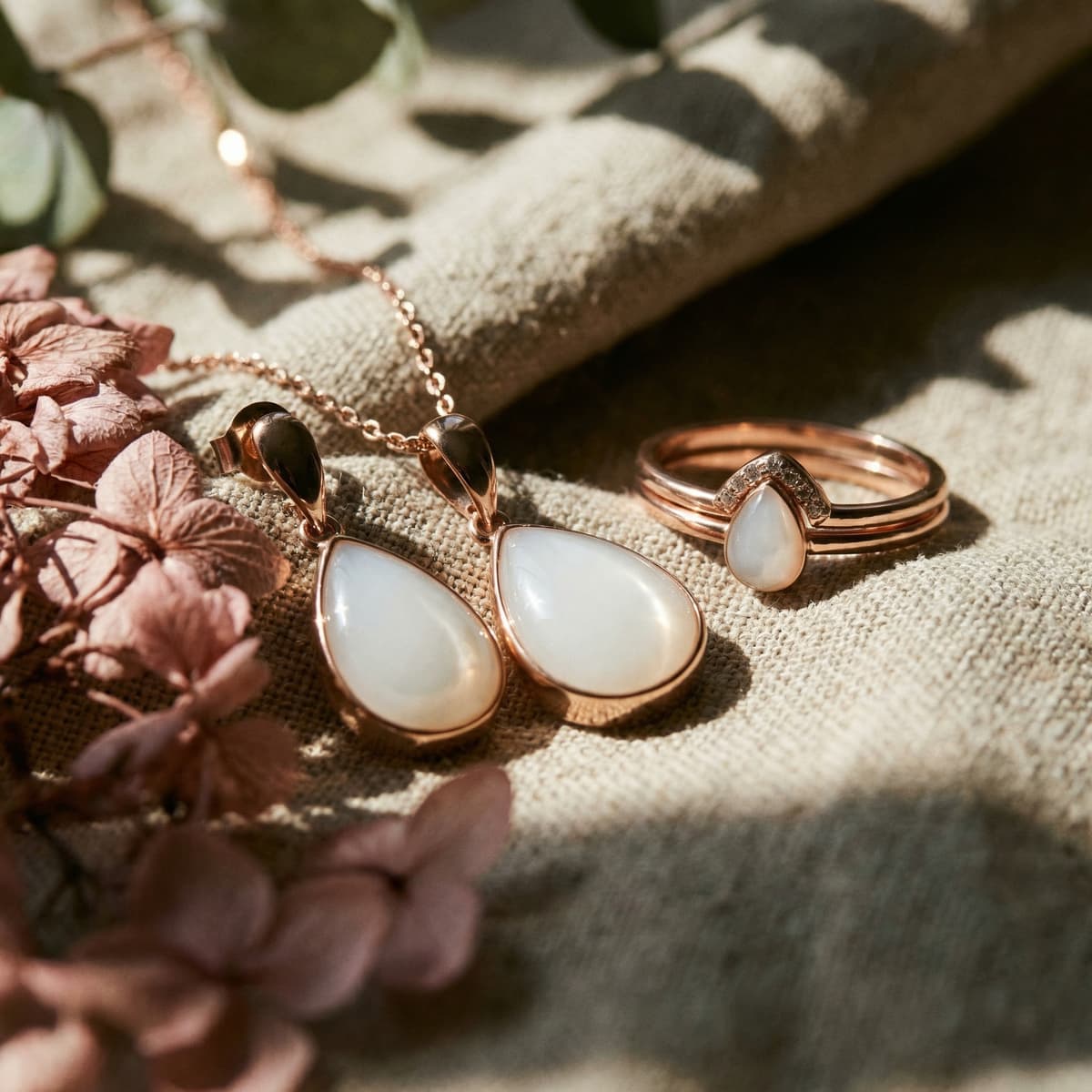 Rose gold breastmilk keepsake jewelry set with teardrop pendant necklace, matching earrings, and ring featuring milky white resin stones, offering an elegant alternative to drying up milk for preservation.