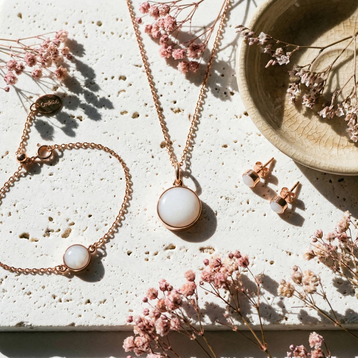 Rose-gold breastmilk jewelry set with round white resin pendant necklace, matching stud earrings, and a delicate bracelet accented with dried pink flowers—an elegant end of breastfeeding gift for moms.