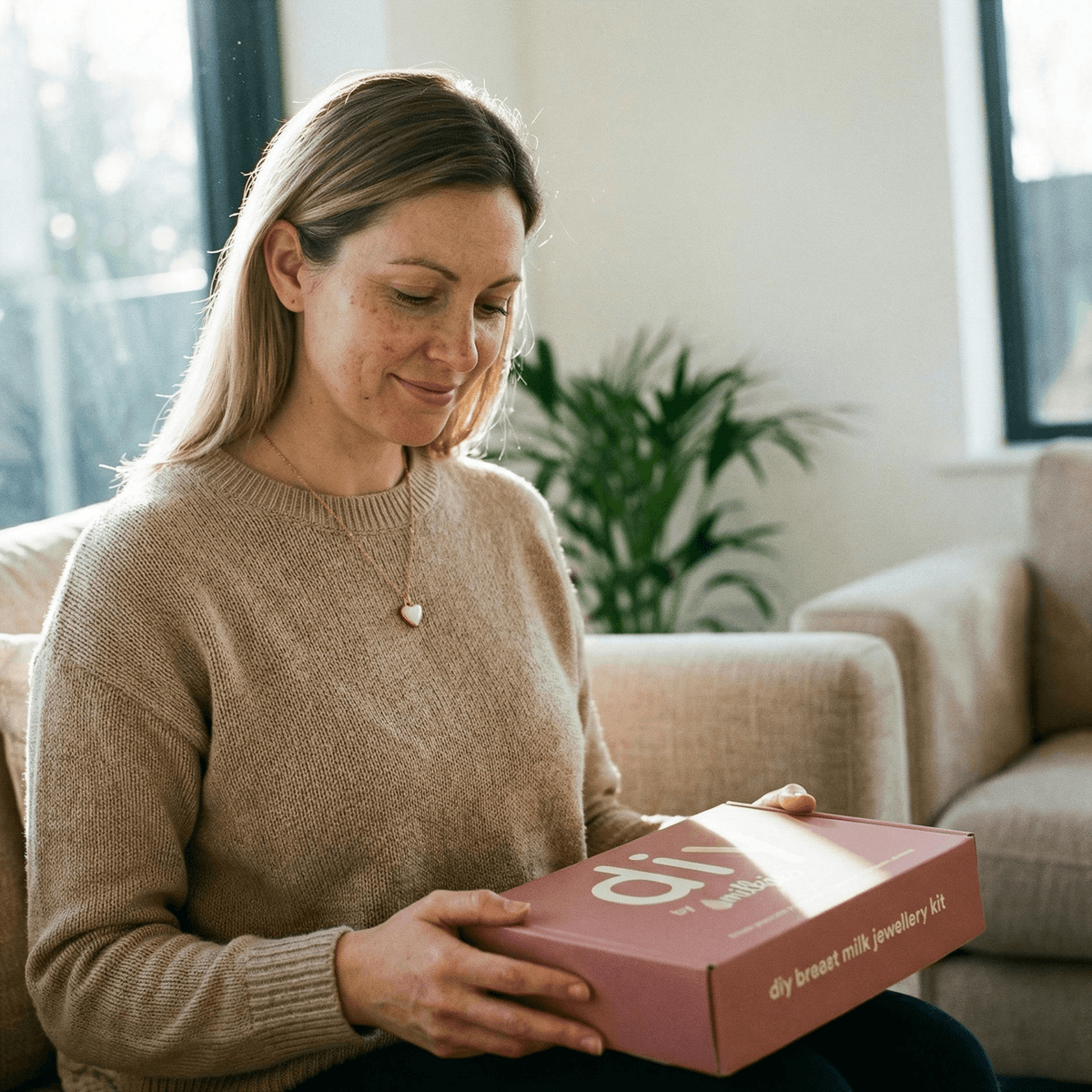 Woman at home holding a DIY by MILKIES breast milk jewellery kit box, a convenient at-home way to create a last feed keepsake resin jewellery piece in privacy.