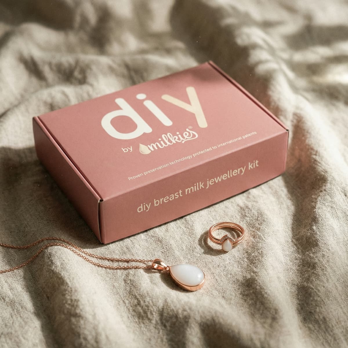 Elegant push present ideas featuring DIY by MILKIES breast milk jewelry kit box with rose-gold ring and teardrop pendant necklace displayed on soft fabric