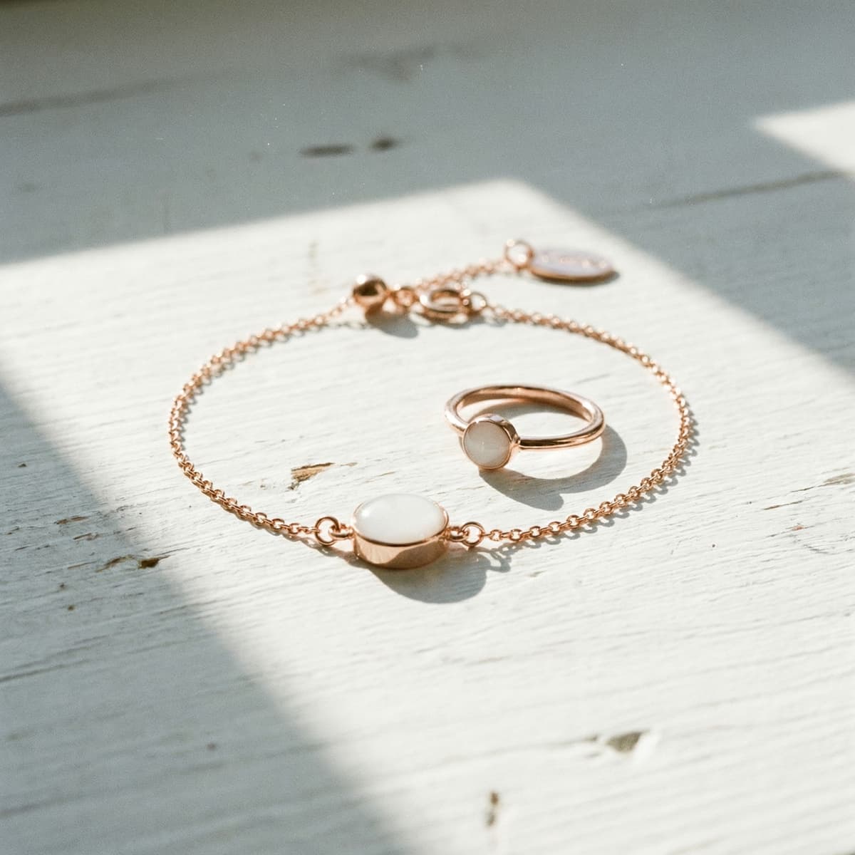 Rose gold bracelet and matching ring with milky white resin stones made using a breastmilk bracelet diy kit, photographed in natural light on a white wooden surface.
