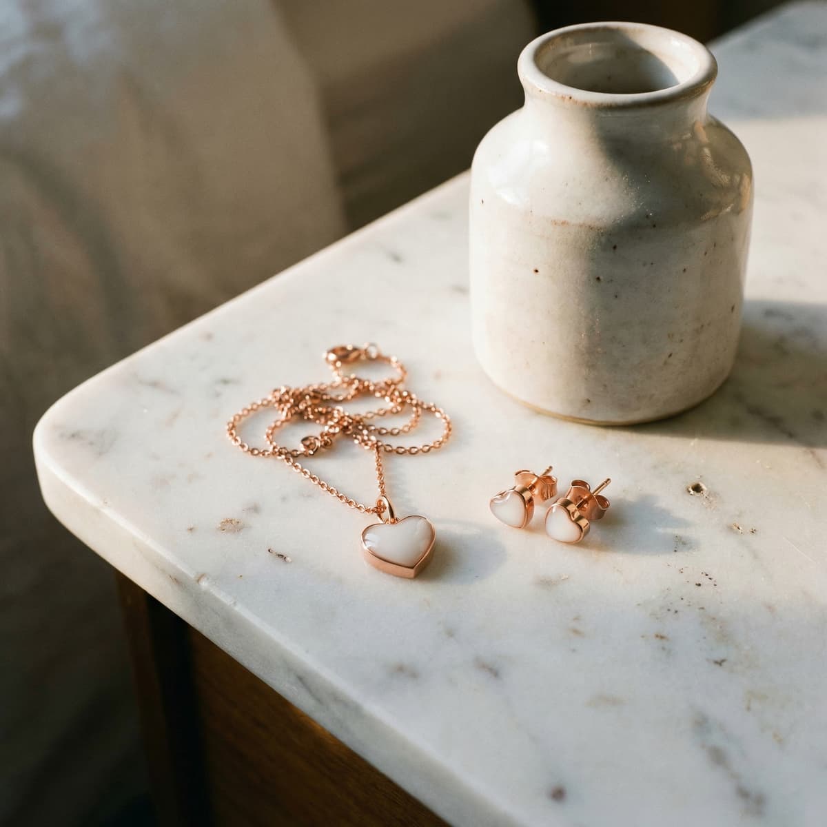 Rose gold heart necklace and matching heart stud earrings with milky white resin displayed on a marble tabletop beside a ceramic vase, showcasing a breastmilk jewellery diy kit keepsake set.