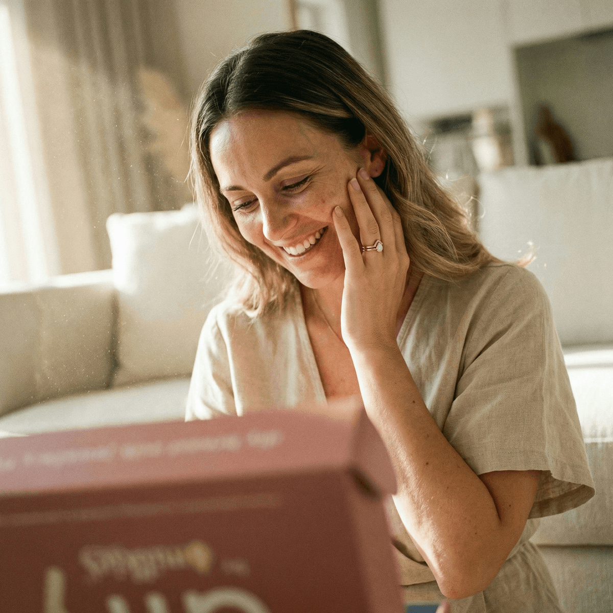 Smiling mom at home admiring her handmade ring, showing why DIY by MILKIES is ideal for creating diy breastmilk rings privately with an easy at-home keepsake kit.