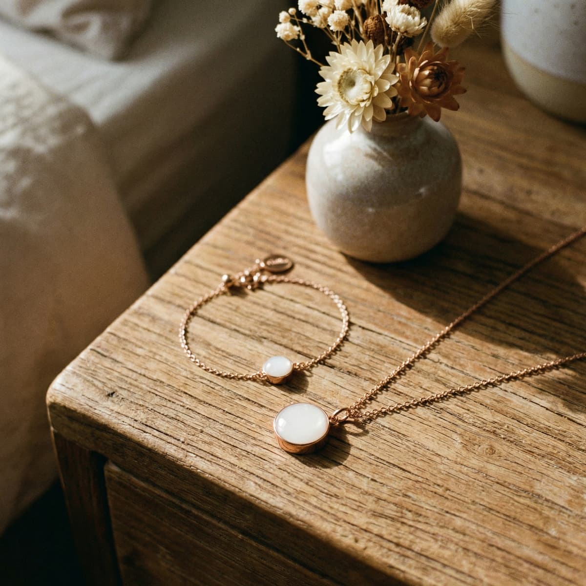 Rose-gold bracelet and necklace breastmilk keepsake jewelry set displayed as an elegant push present, with milky white resin stones on a rustic wooden table beside dried flowers
