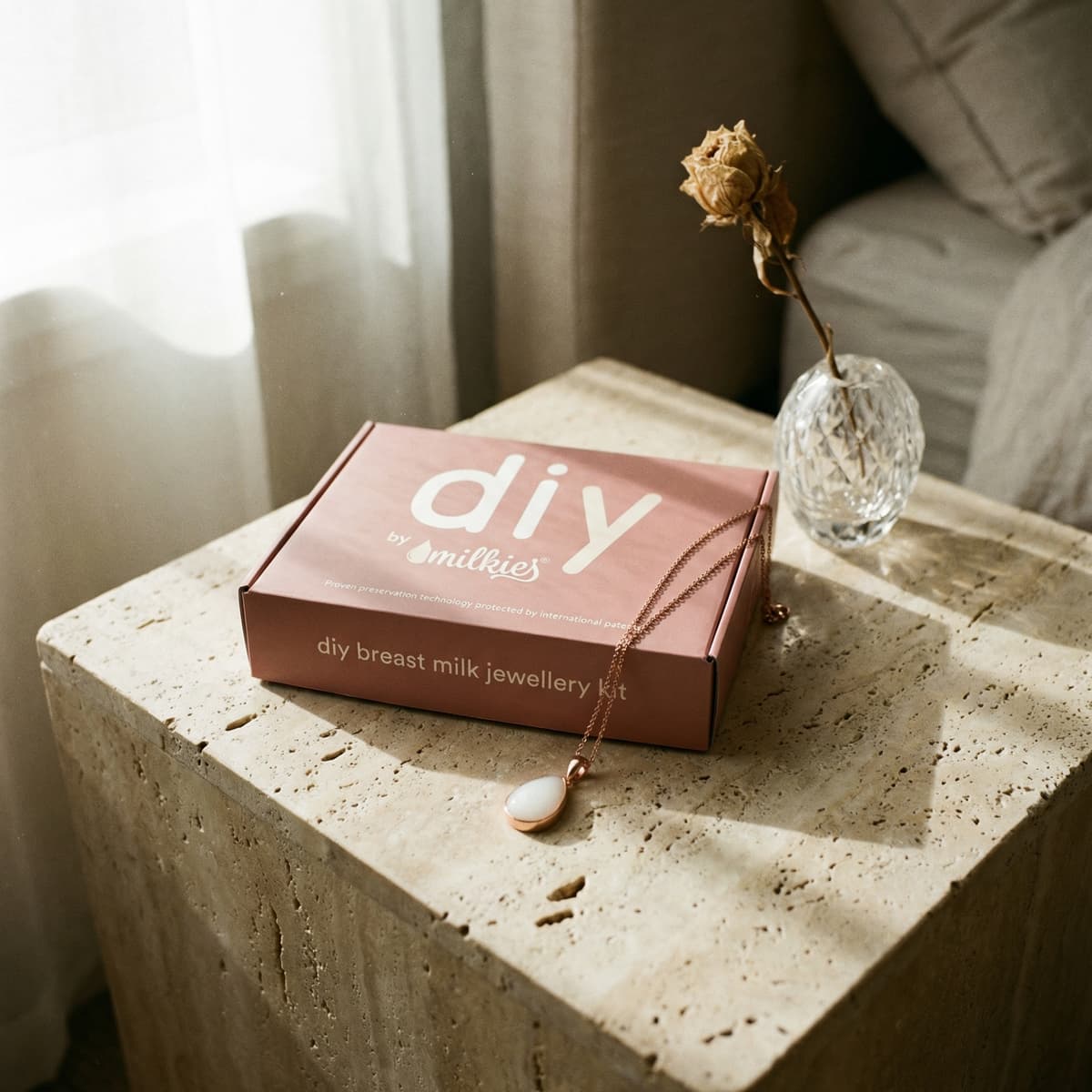 DIY by Milkies breast milk jewellery kit box with rose-gold pendant necklace on a stone table in soft window light, a sentimental push present for new moms